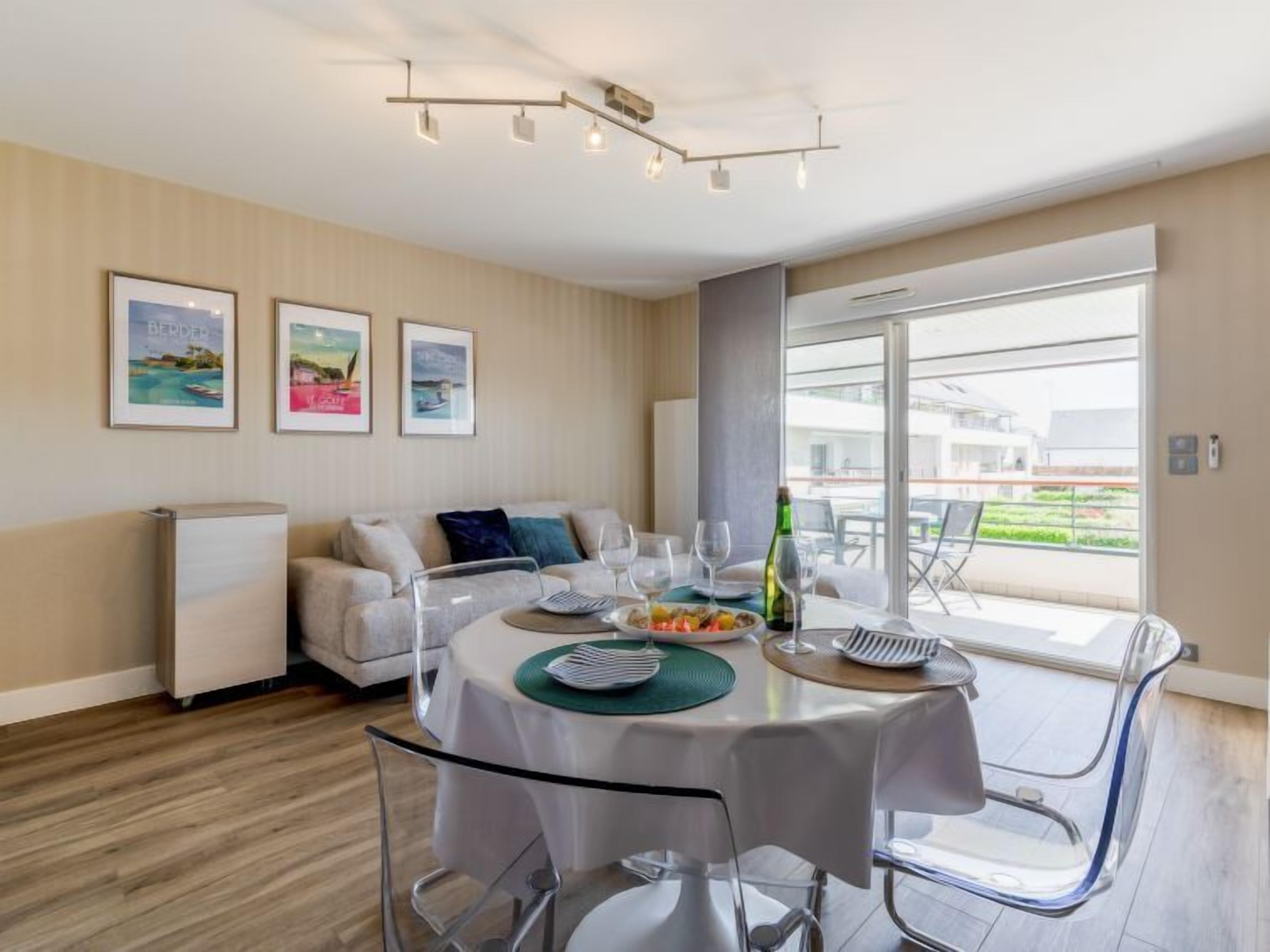 A modern dining area with a round table, clear chairs, and a view of the outdoors.