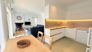 A compact living space with a dining area, a sofa, a TV, and a kitchen with modern appliances. - Ore05 (Rosas / Roses)