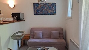 A compact living space with a sofa, a coffee table, a bar stool, and a pendant light. - Vacation home in Soulac near the ocean (Soulac-sur-Mer)