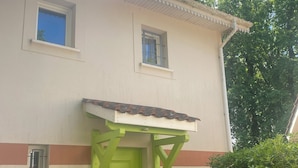 A building with a green door, two windows, and a small porch area. - Vacation home in Soulac near the ocean (Soulac-sur-Mer)