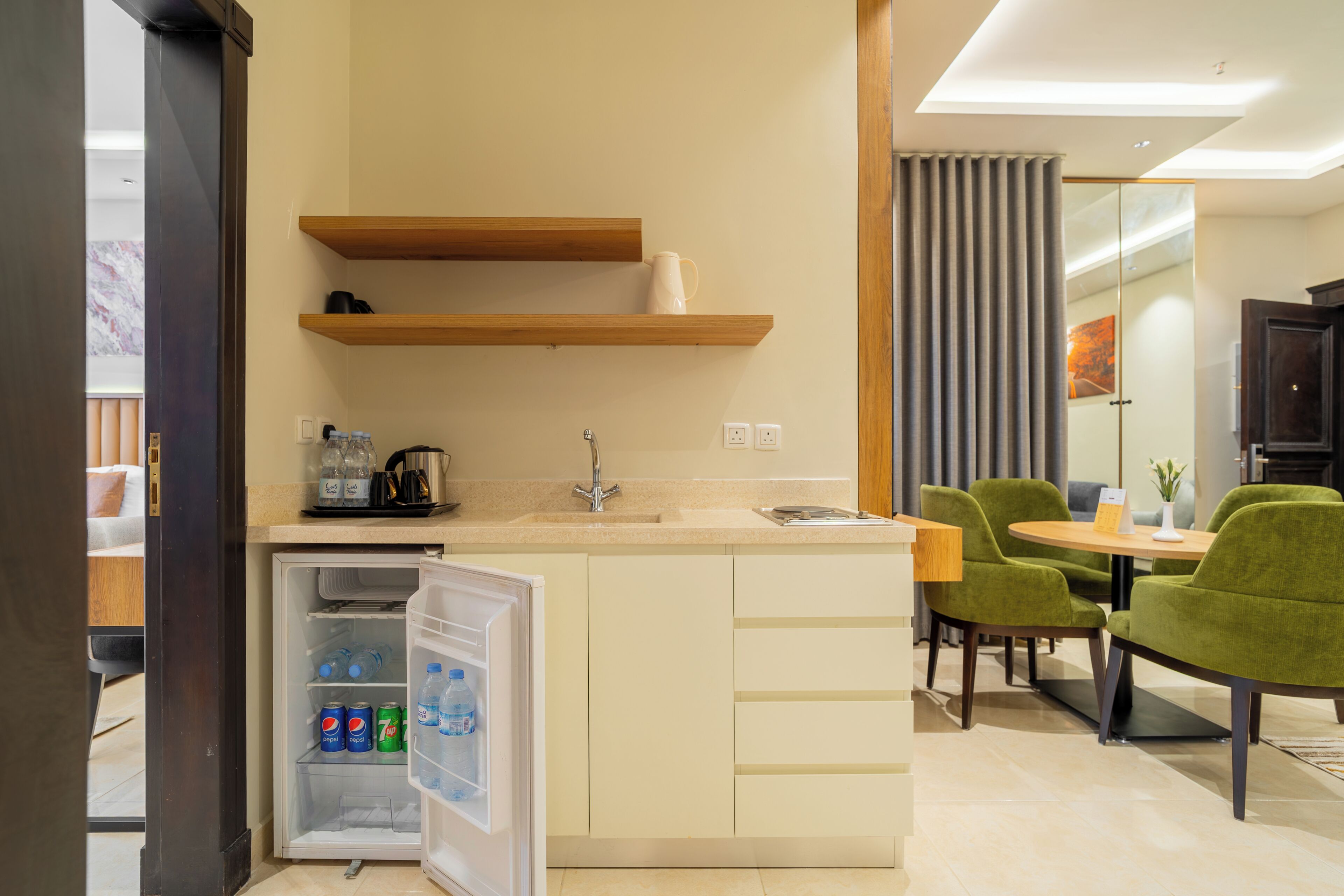 A compact kitchenette with a built-in refrigerator, a sink, and a coffee maker. There is a dining area with a table and chairs.