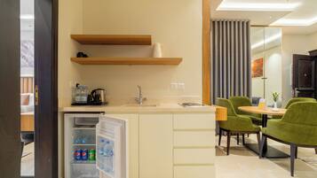 A compact kitchenette with a built-in refrigerator, a sink, and a coffee maker. There is a dining area with a table and chairs.