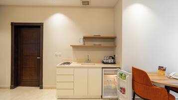 A compact kitchen with a refrigerator, a coffee maker, and a small sink.
