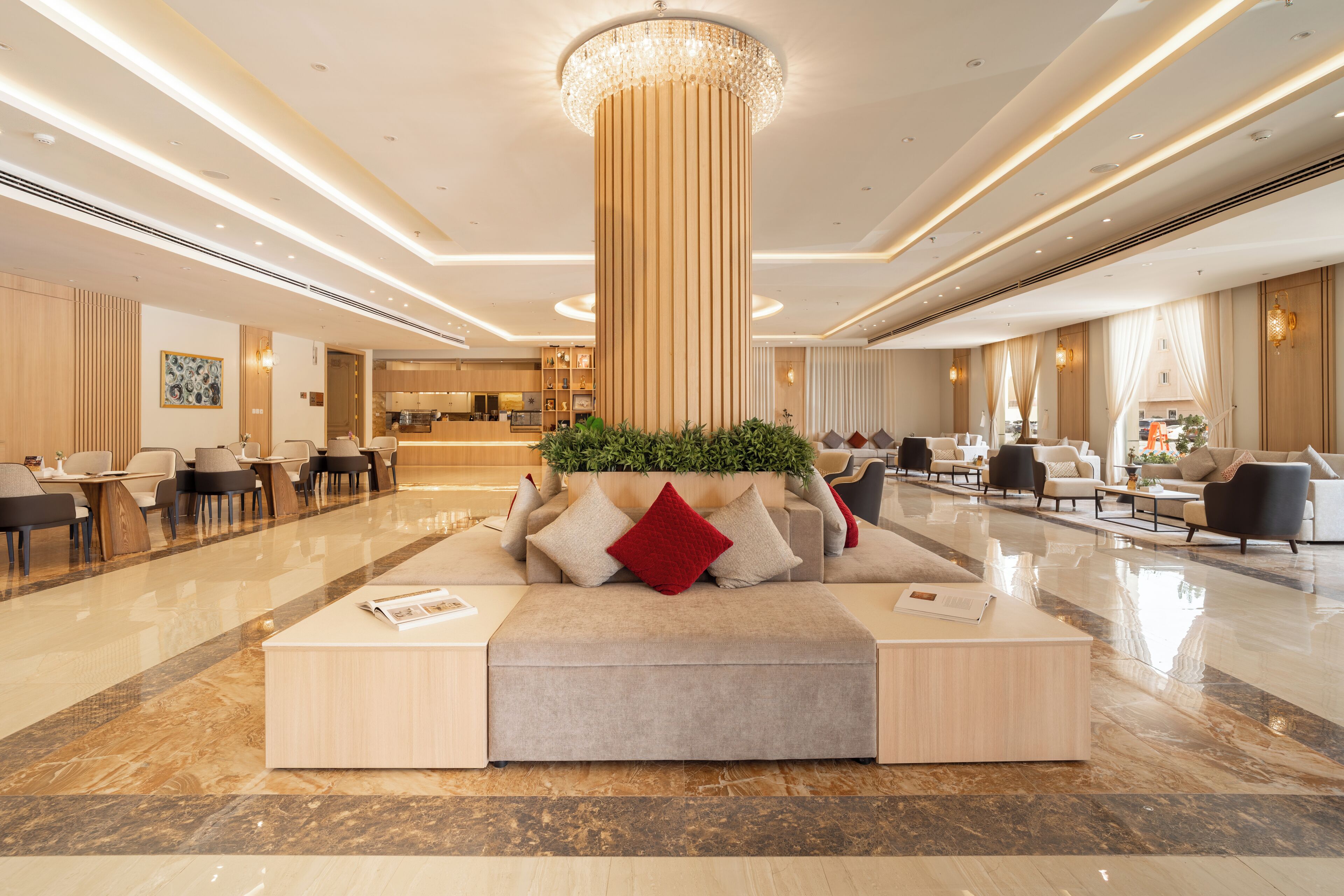 A spacious lobby with a central seating area, a reception desk, and a modern chandelier.
