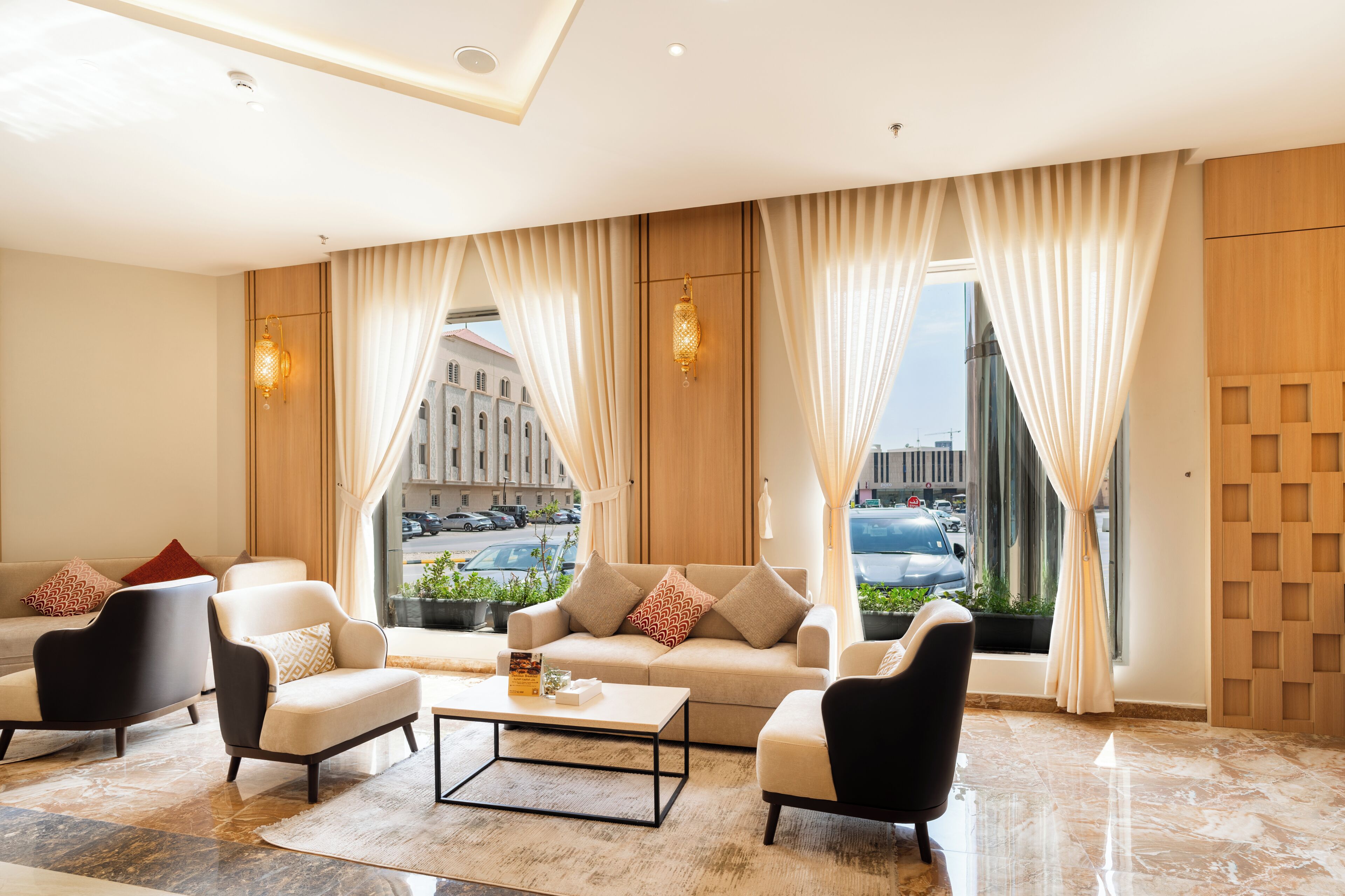 A modern hotel lobby with a seating area, large windows, and a view of the cityscape.