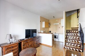 A modern kitchen with a built-in stove, a dining area with a wooden table, and a staircase with a geometric design.