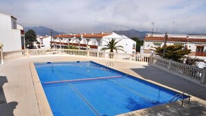 A rectangular swimming pool with clear blue water, surrounded by a white fence and a paved walkway. - LOS ANGELES 53 Roses (Rosas / Roses)