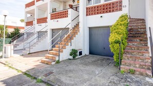 A multi-story building with a staircase, a garage door, and a small garden area. - LOS ANGELES 53 Roses (Rosas / Roses)