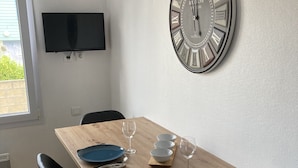 Un comedor con una mesa de madera, sillas negras y un gran reloj de pared.