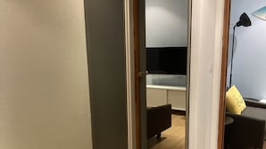 Un pasillo con una puerta corredera que da a una habitación con cama, escritorio y silla.