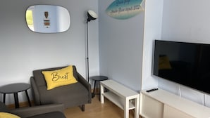 Una sala de estar moderna con un sofá, un banco, un televisor y un espejo montado en la pared.