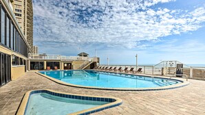 A rooftop swimming pool with a view of the ocean, surrounded by lounge chairs and a building with balconies. - Oceanfront, Fourth-Floor Condo on Daytona Beach! (Daytona Beach)