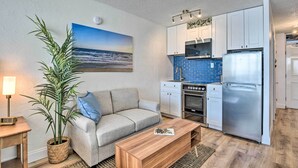 A compact living space with a kitchenette, a sofa, a coffee table, and a large potted plant. - Oceanfront, Fourth-Floor Condo on Daytona Beach! (Daytona Beach)