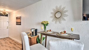 A dining area with a wooden table, two chairs, a coffee machine, and a vase of flowers. - Oceanfront, Fourth-Floor Condo on Daytona Beach! (Daytona Beach)