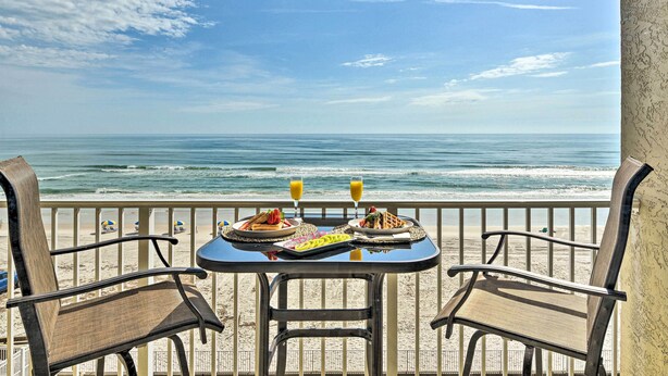 A balcony with a table set for two, overlooking the ocean. - Oceanfront, Fourth-Floor Condo on Daytona Beach! (Daytona Beach)