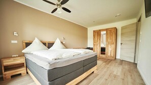 A bedroom with a bed, wooden nightstands, a ceiling fan, and a wardrobe. - Vacation apartment at the Winzerhof with a view of the vineyards. (Stadecken-Elsheim)
