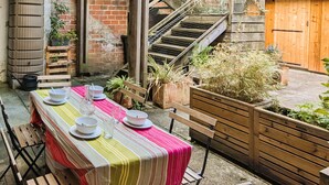 A dining area with a table set for four, surrounded by potted plants and a wooden bench. - Central Arcachon: Modern 2BR Apartment with Terrace, 400m from Beach (Arcachon)