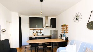A compact living space with a kitchenette, a dining area, and a seating area with a sofa and chairs. - Central Arcachon: Modern 2BR Apartment with Terrace, 400m from Beach (Arcachon)