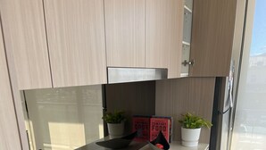 Cocina compacta con estufa a gas, cafetera y dos macetas.