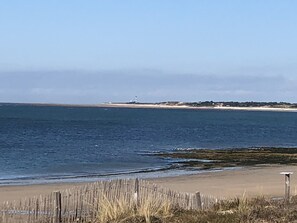 A beach with a lighthouse in the distance, a wooden fence, and a clear sky. - Charming renovated country house Chéray Oléron ( 3 stars) (saint georges d'oléron)