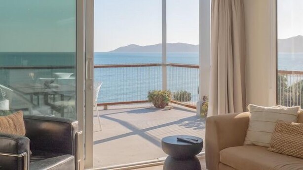 Ein Balkon mit Blick auf das Meer und die Berge, eine Couch und ein Tisch.