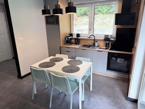 Een kleine keuken met een eethoek, een magnetron, een koffiezetapparaat en een inbouwoven.
