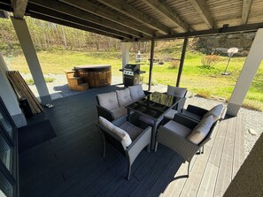 Een terras buiten met een eethoek, een jacuzzi en een barbecue.
