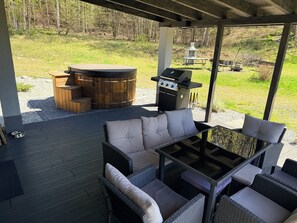 Een terras buiten met een barbecue, een zithoek en een jacuzzi.