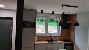 Una cocina con microondas, lavabo e iluminación colgante moderna.