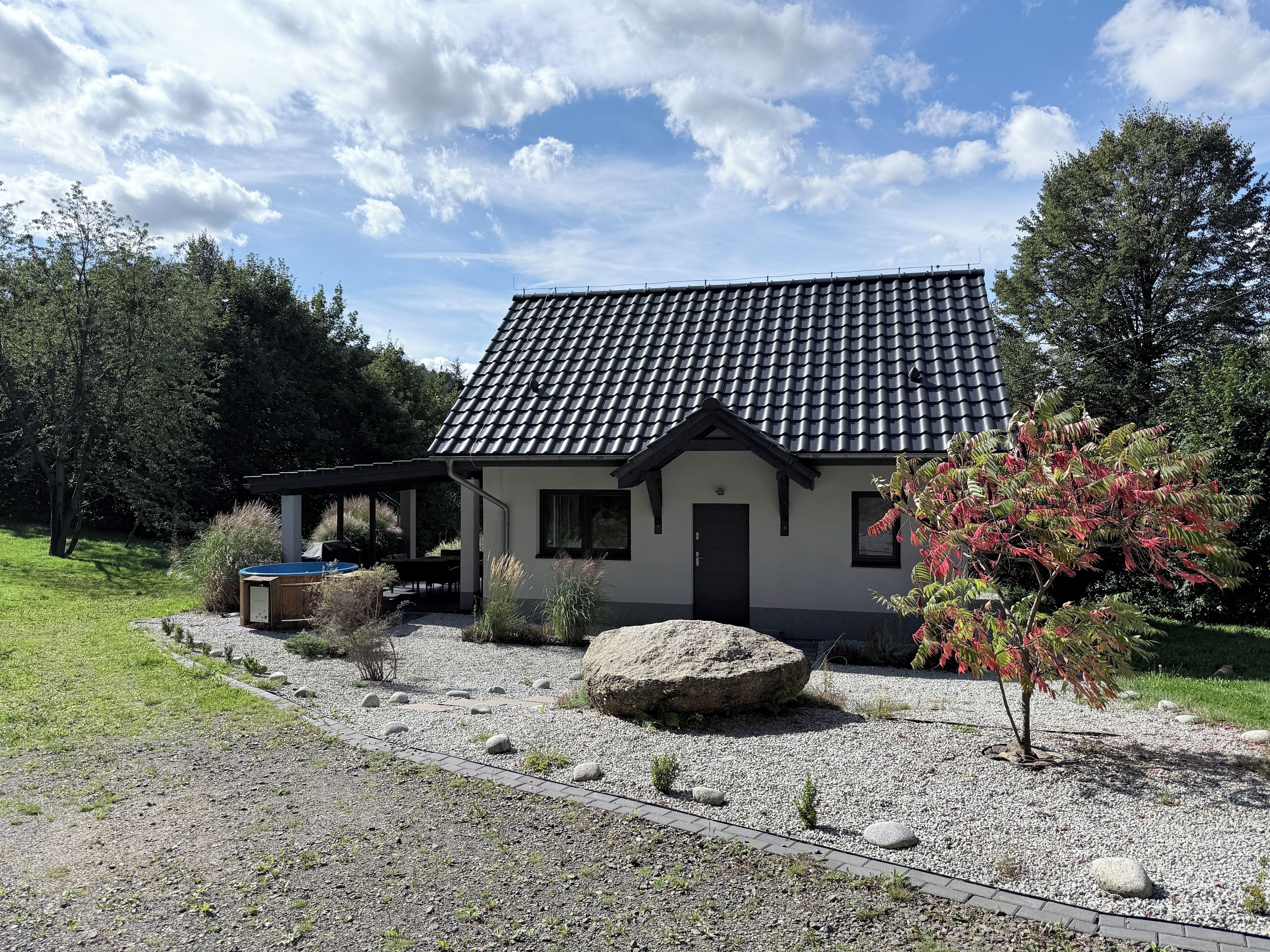A house with a tiled roof, a covered patio, and a gravel driveway.