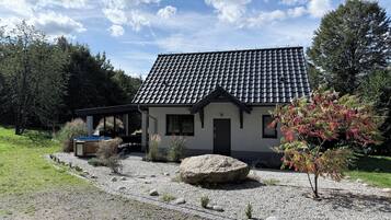A house with a tiled roof, a covered patio, and a gravel driveway.