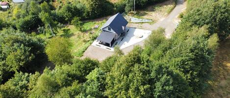 Eine Vogelperspektive zeigt ein Haus, umgeben von üppigem Grün, mit einer gepflasterten Auffahrt, die zum Eingang führt.
