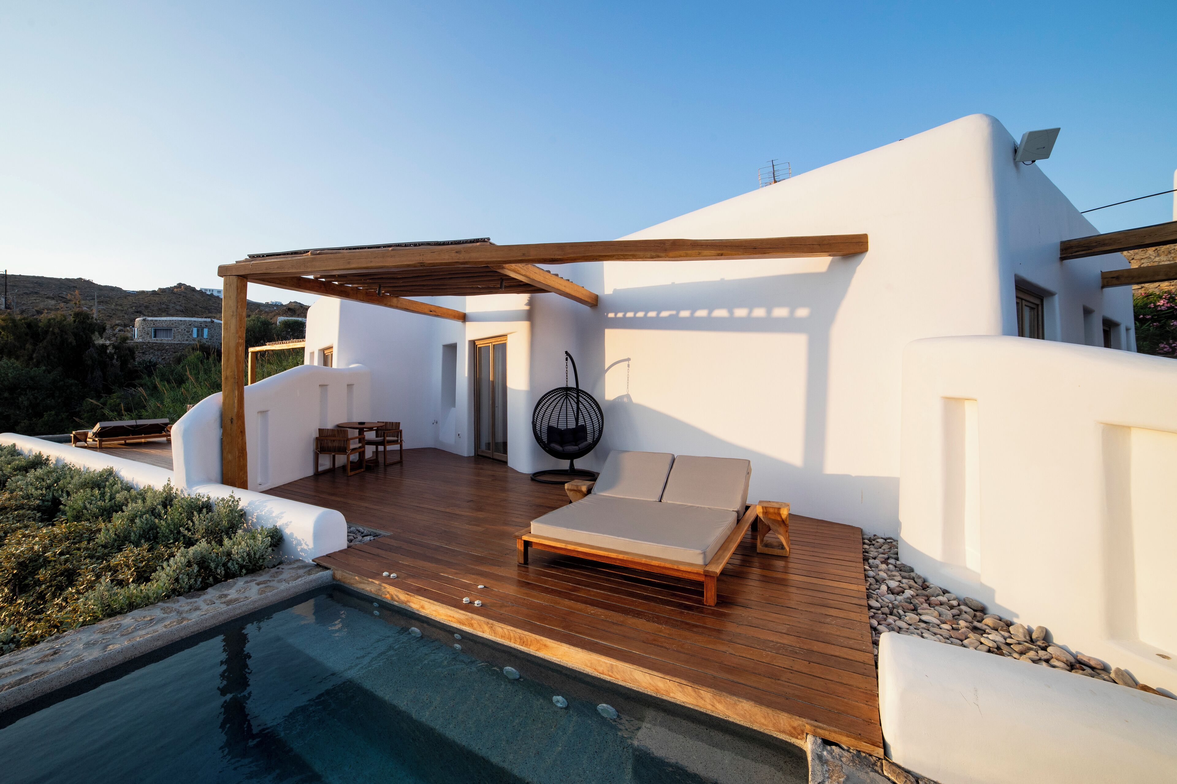 Ein moderner Außenbereich mit Holzterrasse, Pool und Liegestuhl.