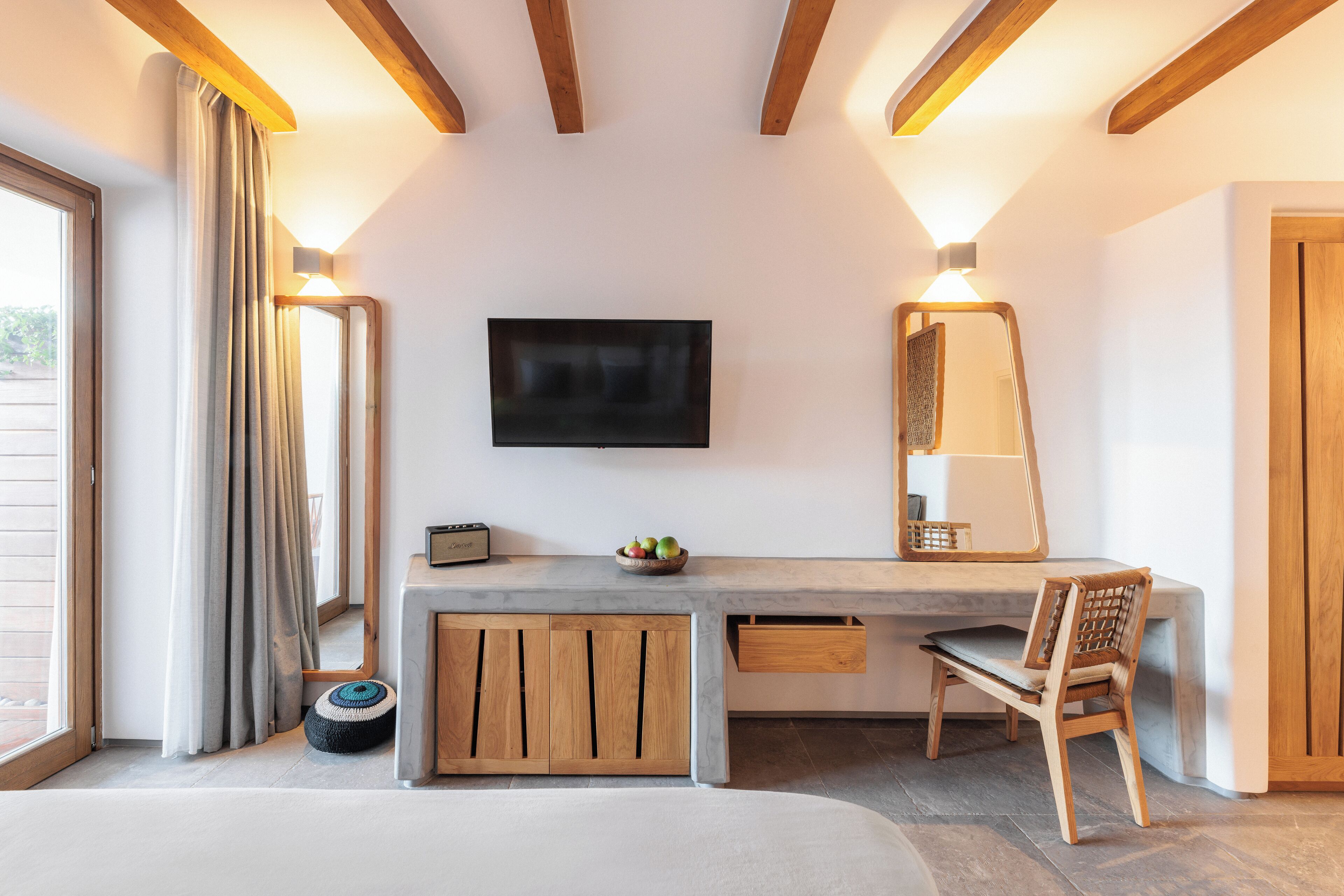 Una habitación moderna con una cama grande, un escritorio con televisor de pantalla plana, armarios de madera y un espejo.