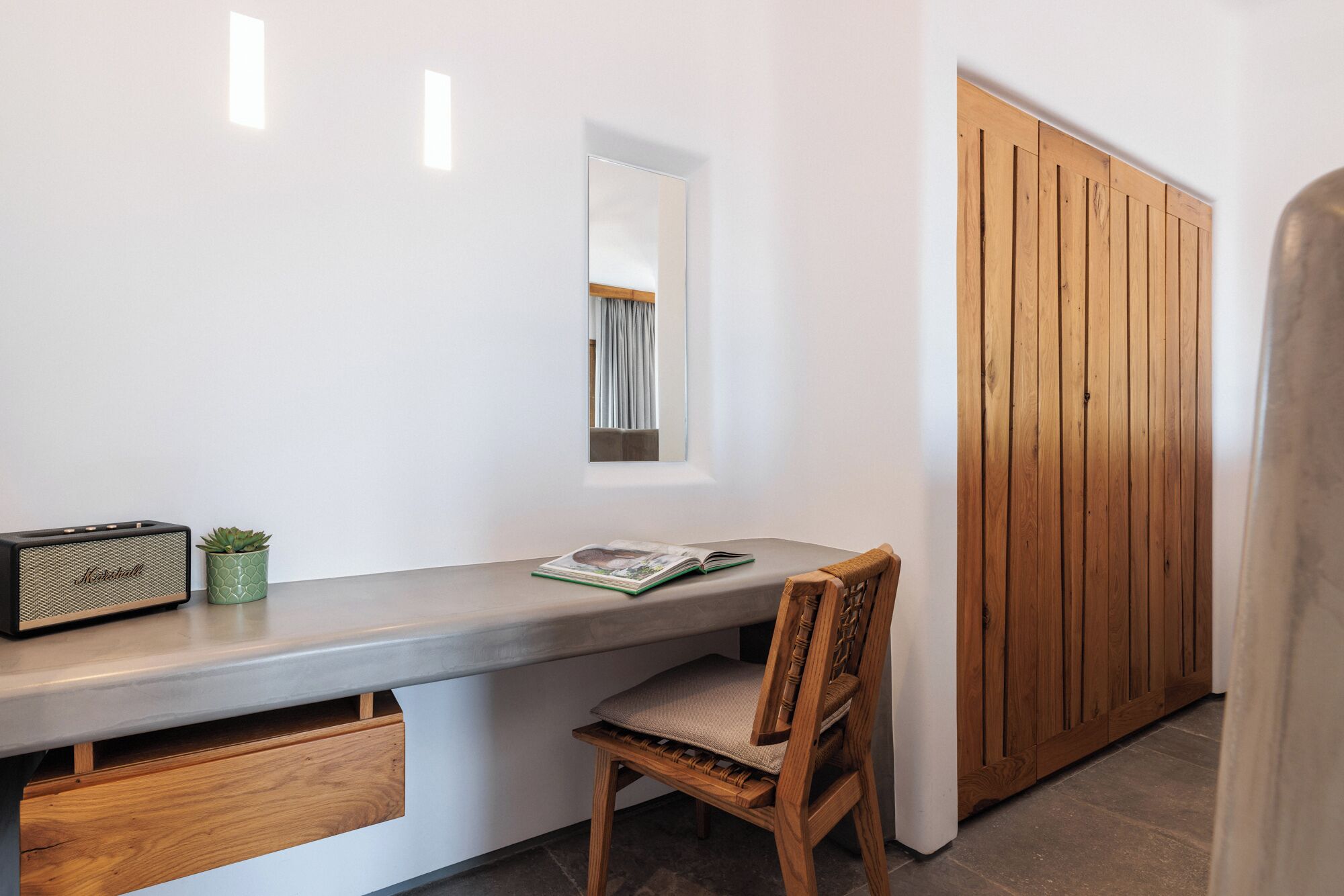 A modern interior with a wooden desk, a chair, a small potted plant, and a wooden wardrobe.
