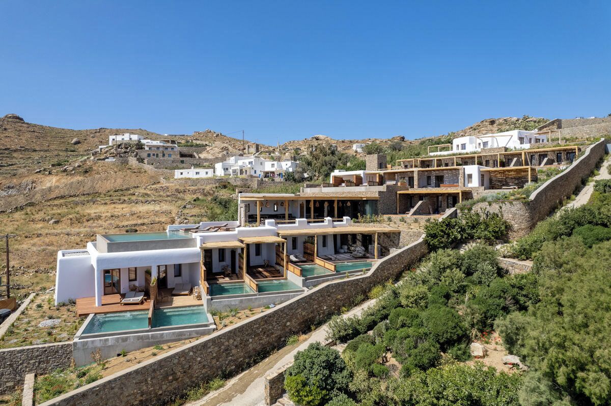 A hillside property with multiple white buildings, each with a pool and outdoor seating.