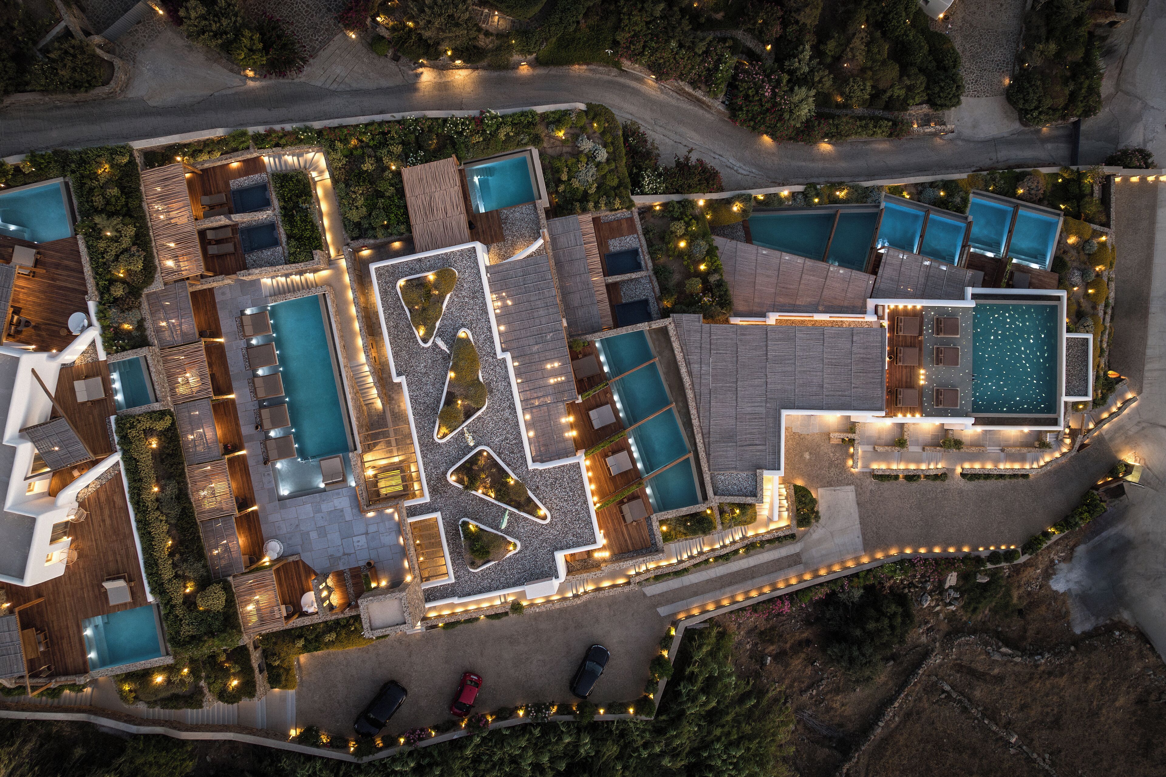Vista aérea de un resort con varias piscinas, zonas de estar al aire libre y senderos bien iluminados.