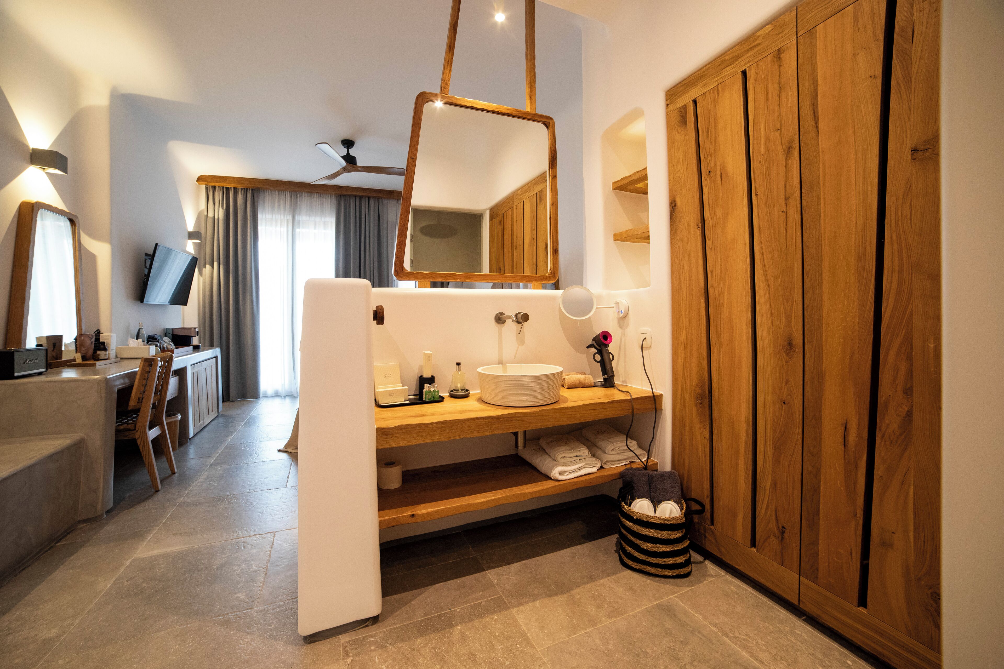 Un baño moderno con tocador de madera, un espejo grande y un lavamanos.