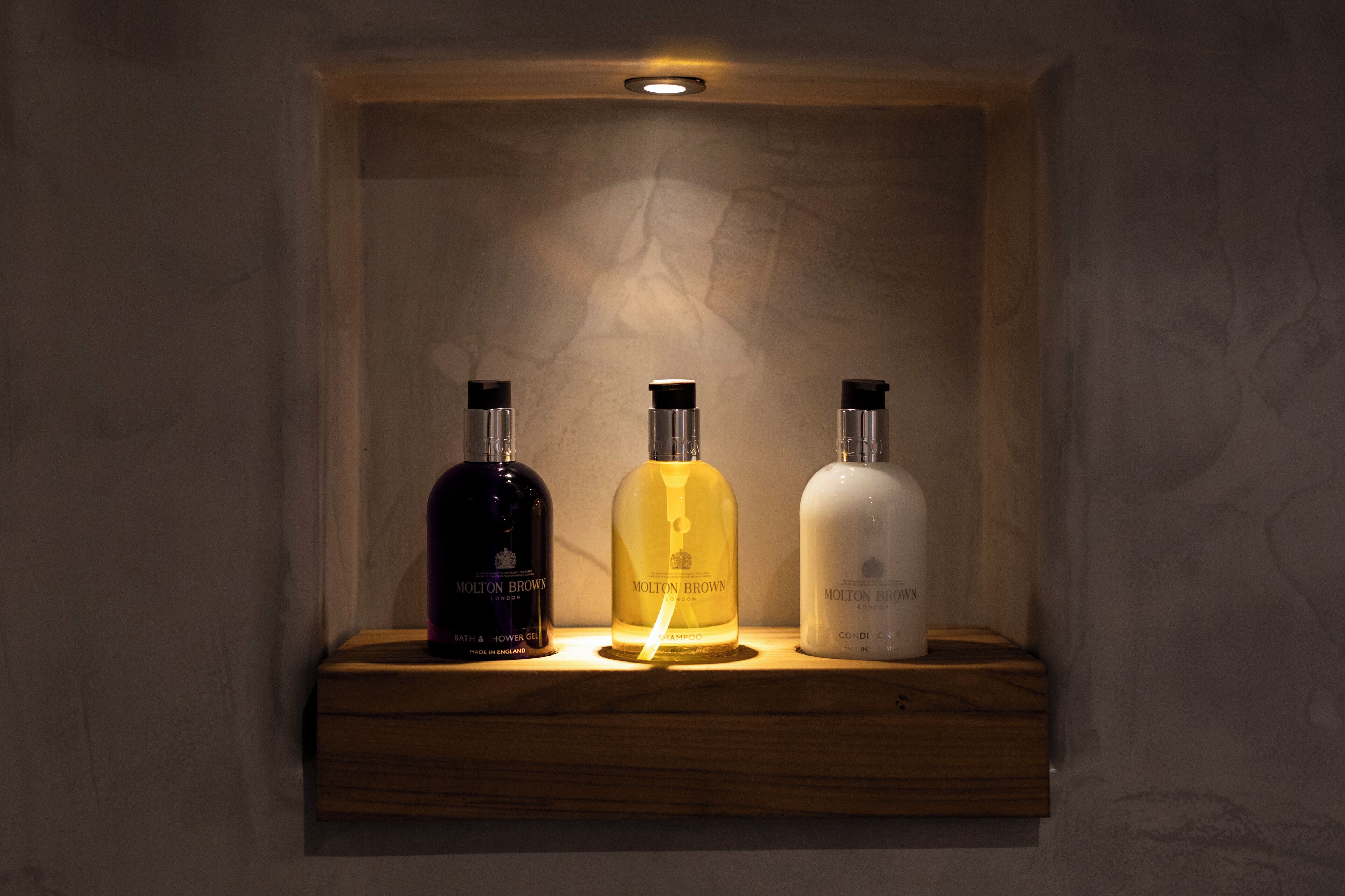Una estantería con tres botellas de productos Molton Brown.
