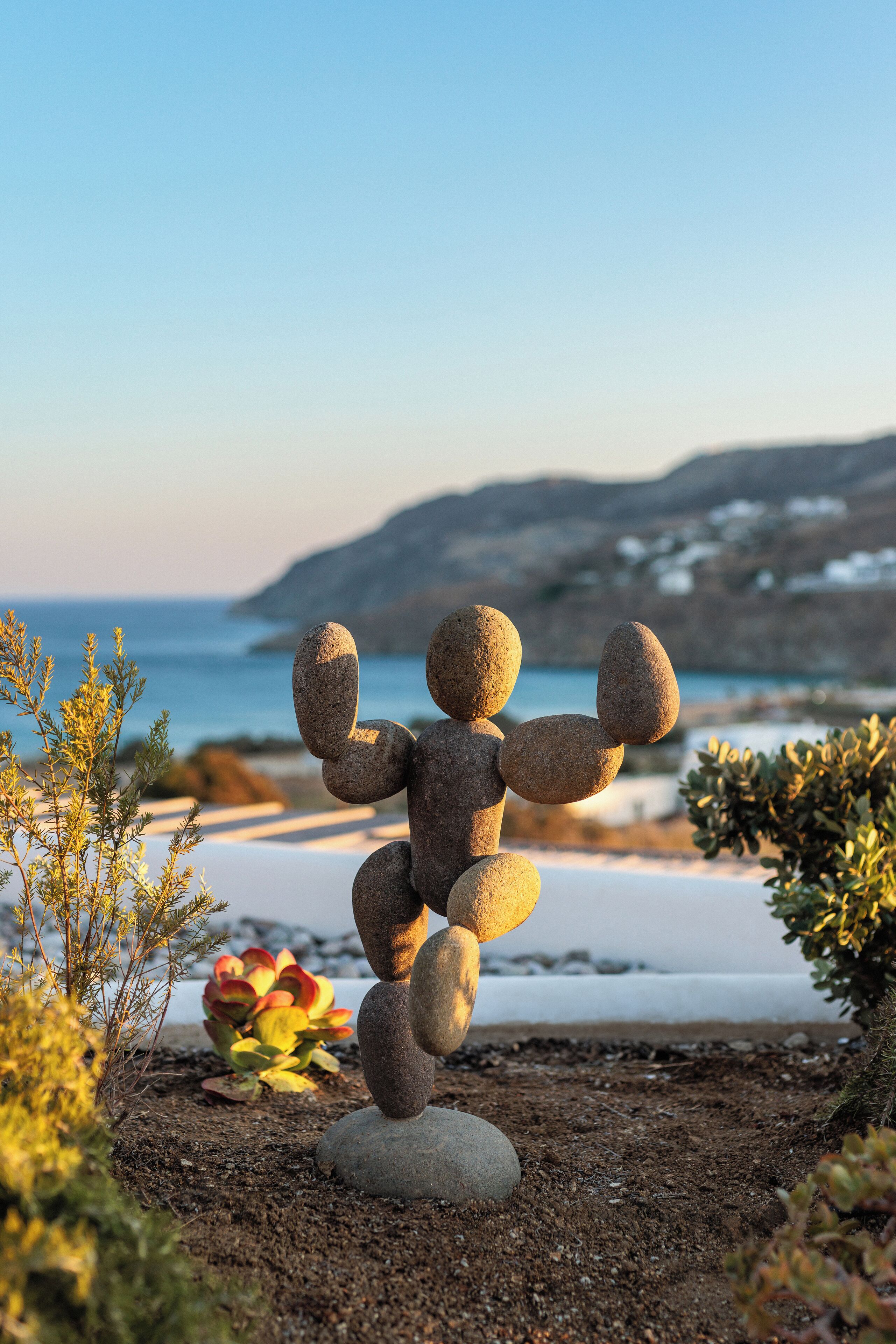 A stone sculpture in a garden with a coastal view.