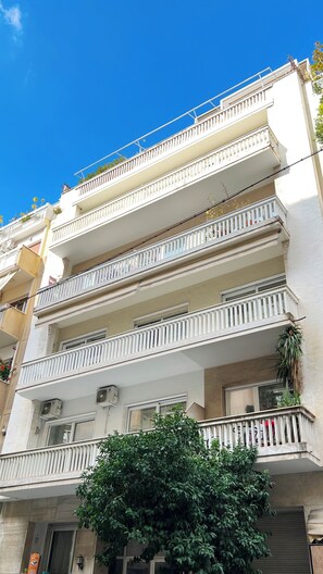A multi-story building with balconies, air conditioning units, and a tree in front. - A cosy studio in the heart of the upscale neighborhood of Kolonaki (Athens)