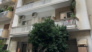 A multi-story residential building with balconies, air conditioning units, and potted plants. - A cosy studio in the heart of the upscale neighborhood of Kolonaki (Athens)
