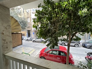 A balcony with a view of a street, a tree, and parked cars. - A cosy studio in the heart of the upscale neighborhood of Kolonaki (Athens)