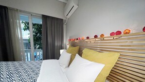 A hotel room with a large bed, a wooden headboard, and a balcony with curtains. - A cosy studio in the heart of the upscale neighborhood of Kolonaki (Athens)
