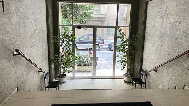 A modern entrance with a glass door, potted plants, and a black rug. - A cosy studio in the heart of the upscale neighborhood of Kolonaki (Athens)