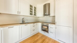 Une cuisine moderne avec des armoires blanches, une hotte de cuisinière en acier inoxydable et un four encastré.