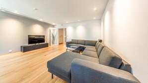 Un salon moderne avec un canapé gris, un téléviseur à écran plat et un plancher en bois.