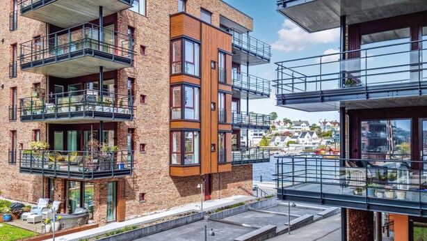 Un immeuble moderne à plusieurs étages, doté de balcons, offrant une vue sur le front de mer et dont la façade est un mélange de briques et de bois.