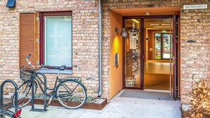 Un bâtiment en briques avec un vélo garé devant, une porte donnant sur l’intérieur et une enseigne au-dessus de la porte.