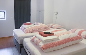 Une chambre d'hôtel avec deux lits, chacun étant équipé de draps à rayures et d'une serviette pliée.
